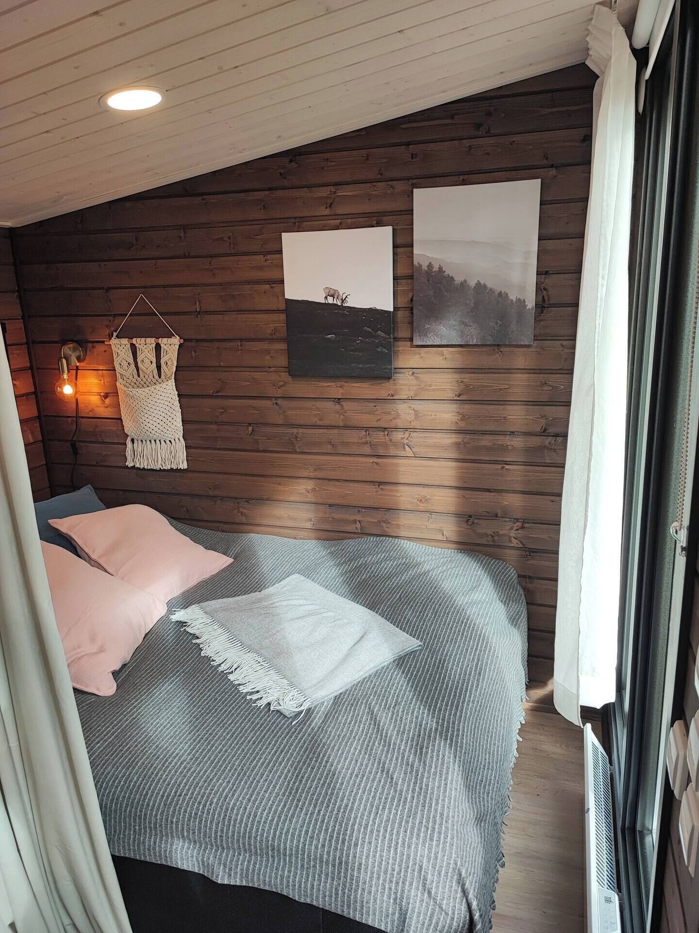 Un dormitorio con una cama, un tapiz de macramé y dos cuadros enmarcados.
