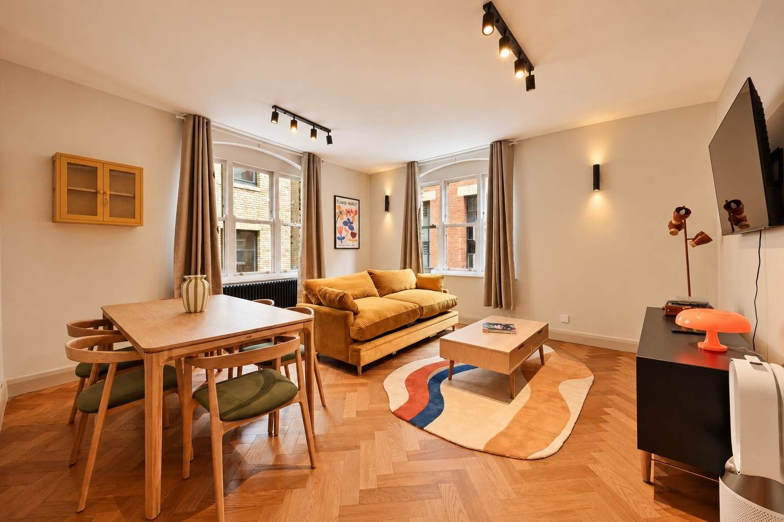 Un salon meublé comprenant un canapé, une table à manger avec des chaises, une table basse et un meuble pour la télévision avec une lampe.