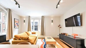 Un salon moderne avec un canapé, une table basse, un téléviseur et un radiateur.