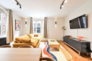 Ein modernes Wohnzimmer mit einer Couch, einem Couchtisch, einem Fernseher und einer Heizung.