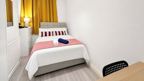 Ein Schlafzimmer mit Bett, Nachttisch, Lampe und Stuhl.