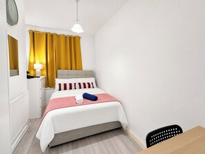 Ein Schlafzimmer mit Bett, Nachttisch, Lampe und Stuhl.
