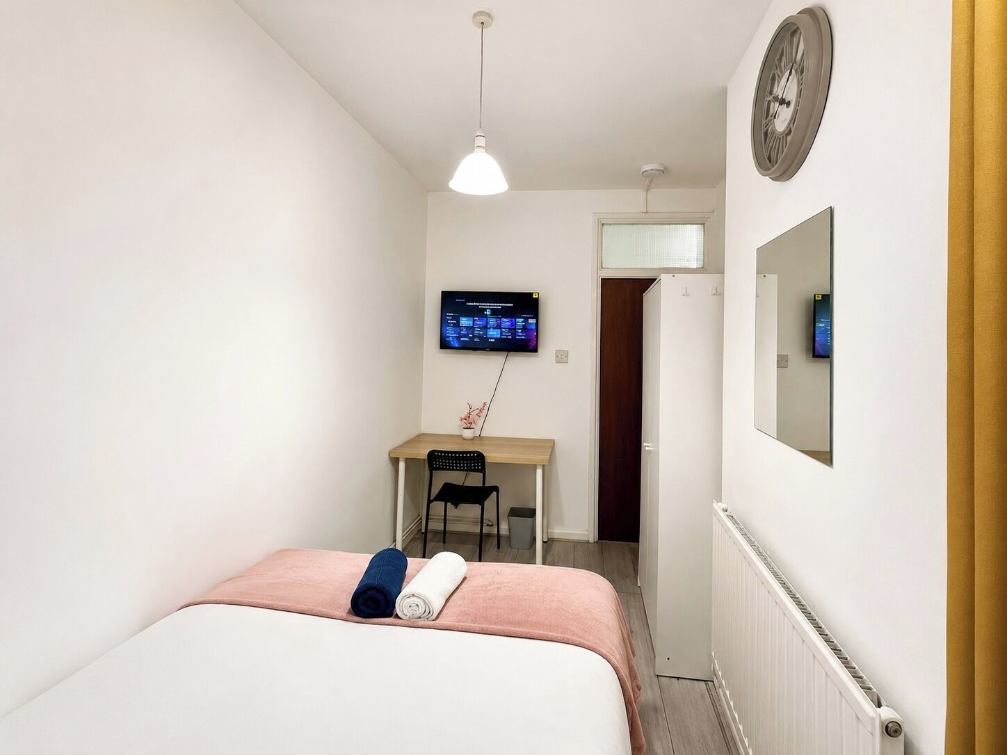 Une chambre d’hôtel équipée d’un lit, d’un bureau, d’une télévision et d’un radiateur.