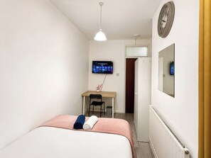Ein Hotelzimmer mit Bett, Schreibtisch, Fernseher und Heizkörper.