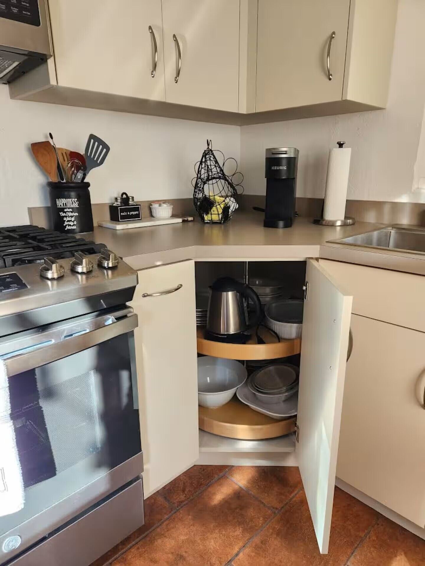 A kitchen with a stove, oven, and a dish rack with pots and pans.