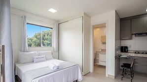 Une chambre d’hôtel comprenant un lit, une fenêtre avec des rideaux, une salle de bain et une kitchenette.