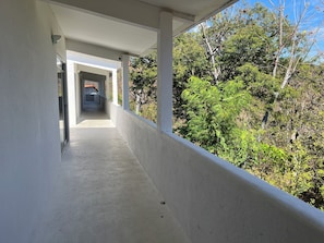 A covered walkway with a view of dense greenery and trees. - Hotel Mare (Santa Maria Huatulco)