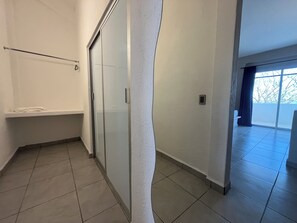 A corridor with a glass door, a white wall, and a tiled floor. - Hotel Mare (Santa Maria Huatulco)