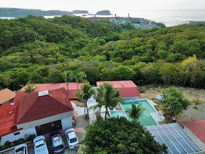 A residential area with a swimming pool, parked cars, and a view of the sea. - Hotel Mare (Santa Maria Huatulco)
