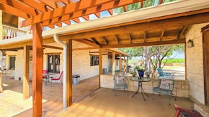An outdoor patio area with stone walls, wooden pergola, and metal furniture. - Sonora Suite - Gruene Cottages (New Braunfels)
