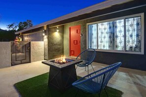 Ein modernes Haus mit Feuerstelle, Sitzgelegenheit im Freien und Garage.