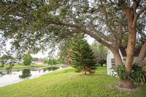 A residential area with a large tree, a pond, and a house. - Treasure Coast Villa 5bd + pool hot tub game room (Port St. Lucie)