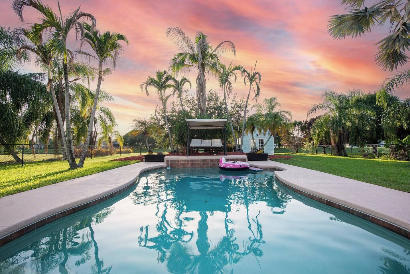 Una piscina con zona de descanso y palmeras.