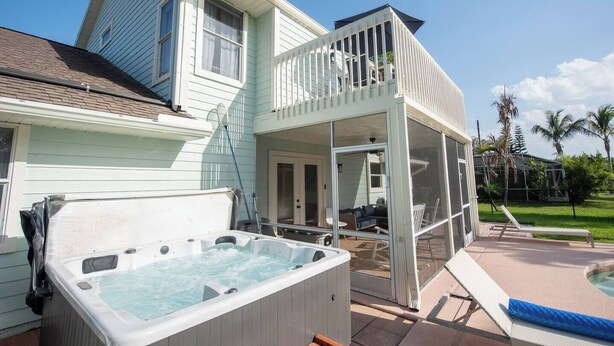 Ein Haus mit einem einsehbaren Veranda, einem Whirlpool und einem Poolbereich.