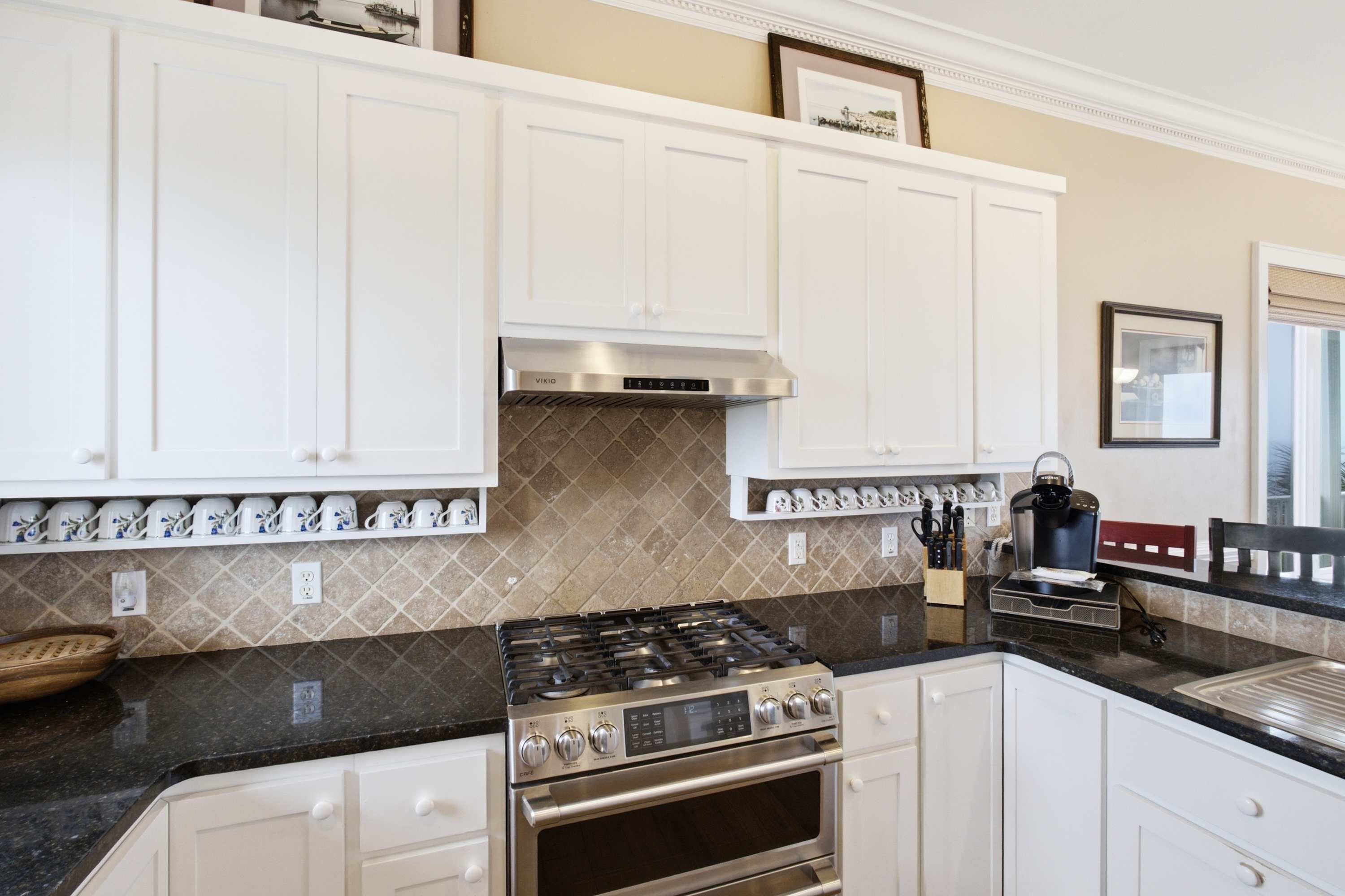 A modern kitchen with white cabinets, a gas stove, and a built-in oven.