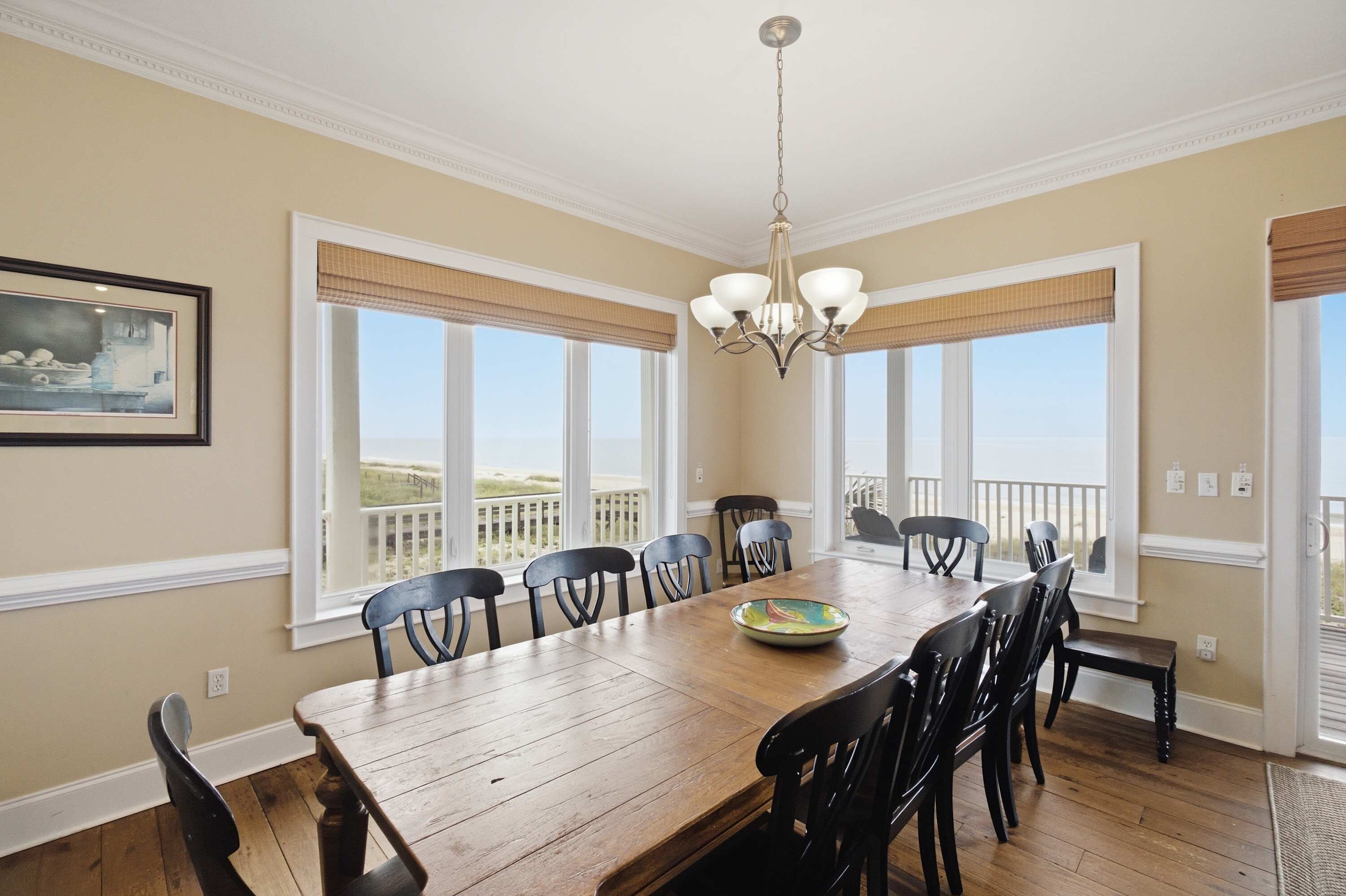 A dining room with a large wooden table, black chairs, and a chandelier.