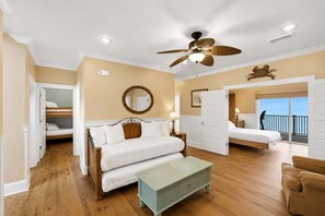 A bedroom with a bed, a ceiling fan, a bedside table, a nightstand, a mirror, and a view of the balcony. - Beachfront Luxury | Pool, Hot Tub, Elevator (Saint George Island)