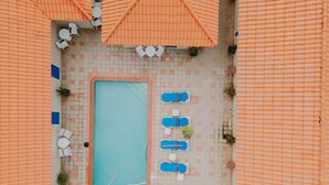 Vista aérea de una zona de piscina con sillones de playa y sombrillas.