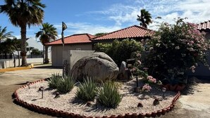 Un edificio con techo de tejas rojas, rodeado por un jardín ajardinado con rocas y plantas.