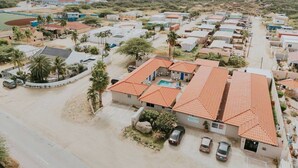 A residential area with multiple houses, a swimming pool, and a road. - Aruba Studio w/ Pool · King Size · Near Beach #13 (Noord)