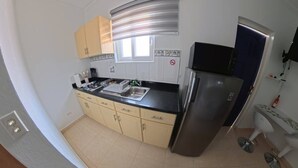 A compact kitchen with a stainless steel refrigerator, a sink, and a window with blinds. - Aruba Studio w/ Pool · King Size · Near Beach #13 (Noord)