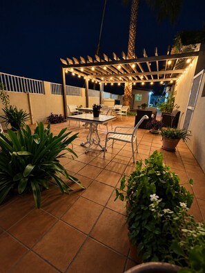 An outdoor patio area with a pergola, seating, and potted plants. - Aruba Retreat w/ Pool · King Bed · #8 (Aruba)