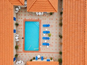 A rooftop pool area with a rectangular pool, lounge chairs, and umbrellas. - Aruba Retreat w/ Pool · King Bed · #8 (Aruba)