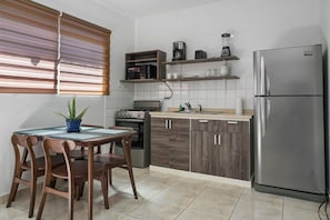 A compact kitchen with a dining table, chairs, a refrigerator, a stove, and a window with blinds. - Aruba Retreat w/ Pool · King Bed · #8 (Aruba)