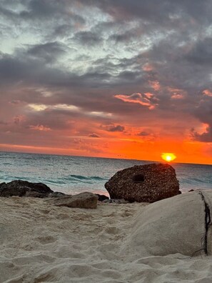 A beach with a sunset, rocky outcrops, and calm sea. - Haven w/ Pool · King Bed · Near Palm Beach #9 (Noord)