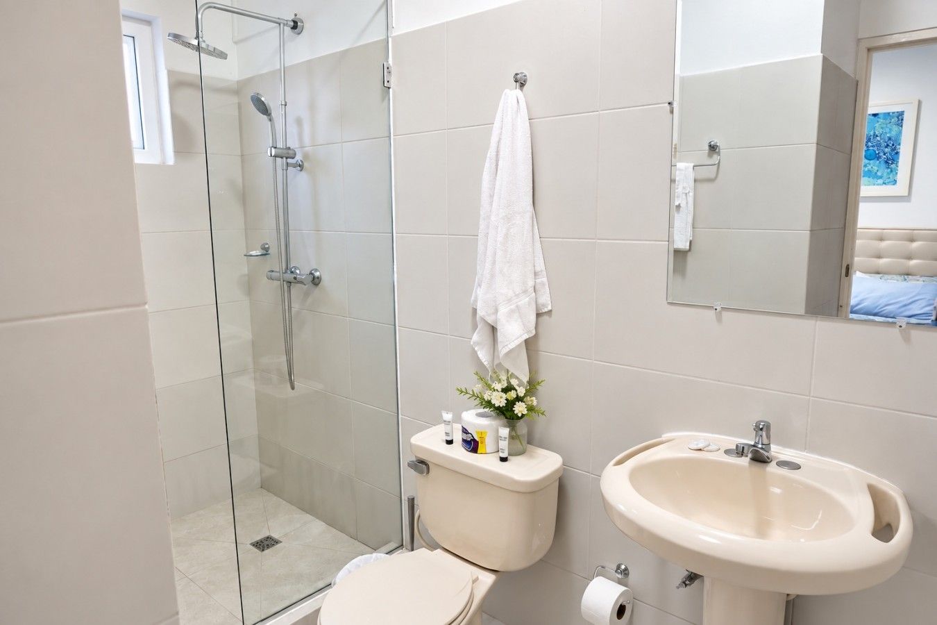 Un baño con ducha envuelta en vidrio, inodoro, lavabo y espejo.