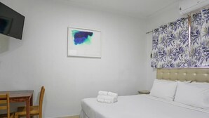 Ett hotellrum med en säng, ett skrivbord och en stol.