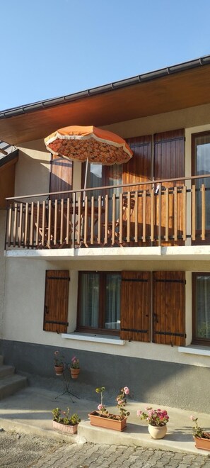 A two-story building with a balcony, wooden shutters, and potted plants. - 150m from ski slopes, 1st floor, balcony, parking, 36m², Valloire (Valloire)
