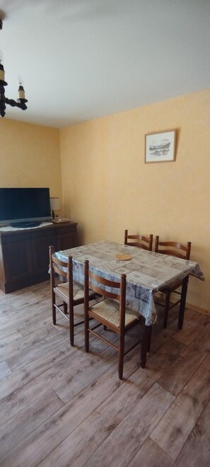 A dining area with a table and chairs, a television on a stand, and a framed picture on the wall. - 150m from ski slopes, 1st floor, balcony, parking, 36m², Valloire (Valloire)