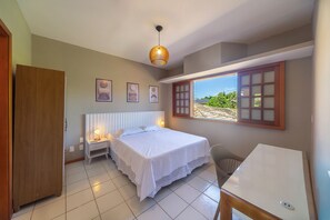 Ein Schlafzimmer mit einem Bett, Nachttischen, einem Schreibtisch und einem Fenster mit Blick.