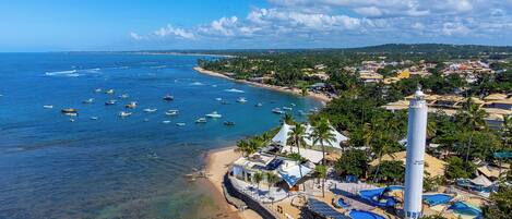 A coastal resort with a lighthouse, clear blue waters, and a sandy beach.