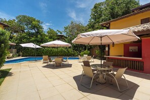 Eine Außenpatio mit Pool, umgeben von viel Grün und einem roten Gebäude.