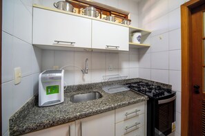 Eine Küche mit Kaffeemaschine, Spüle, Herd und Schränken.