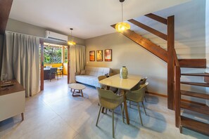 Ein modernes Wohnzimmer mit einer Couch, einem Esstisch, Stühlen und einer Treppe.