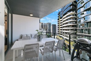 A balcony with a table and chairs, a grill, and a potted plant. - Riverstone Perch Urban Comfort near Brisbane River (Newstead)