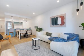 Ein modernes Wohnzimmer mit einer Couch, einem Couchtisch und einem Essbereich mit Stühlen und einem Tisch.