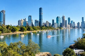 Eine moderne Skyline mit Hochhäusern und einem Fluss mit Booten.