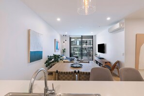 A modern kitchen with a dining area, a large window, and a flat-screen TV. - Riverstone Perch Urban Comfort near Brisbane River (Newstead)