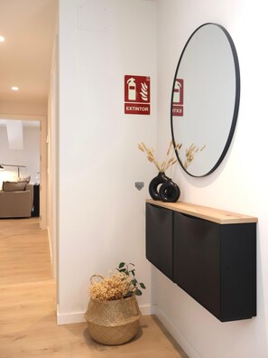 A hallway with a black console, a mirror, and a fire extinguisher sign. - Larrabide Industrial Apartment (Pamplona)