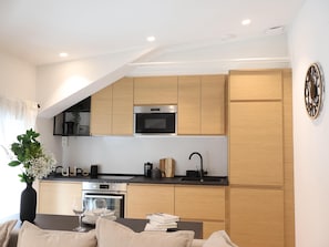 A modern kitchen with wooden cabinets, a built-in oven, and a black countertop.