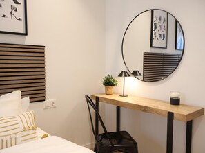 A hotel room with a bed, a bedside table with a lamp, a mirror, and a wall-mounted artwork. - Larrabide Industrial Apartment (Pamplona)