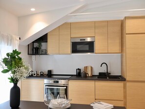 A modern kitchen with wooden cabinets, a built-in oven, and a black countertop. - Larrabide Industrial Apartment (Pamplona)