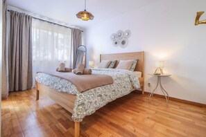 A bedroom with a wooden bed, a bedside table, a mirror, and a wall decoration. - Aroeira Golf & Wave Retreat (Almada)