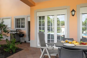 En terrasse med et morgenmadsbord, grill og udsigt til en swimmingpool.