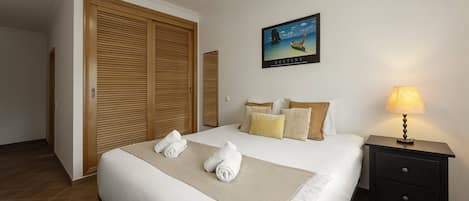 A hotel room with a bed, a nightstand, a lamp, a painting, and a wardrobe.