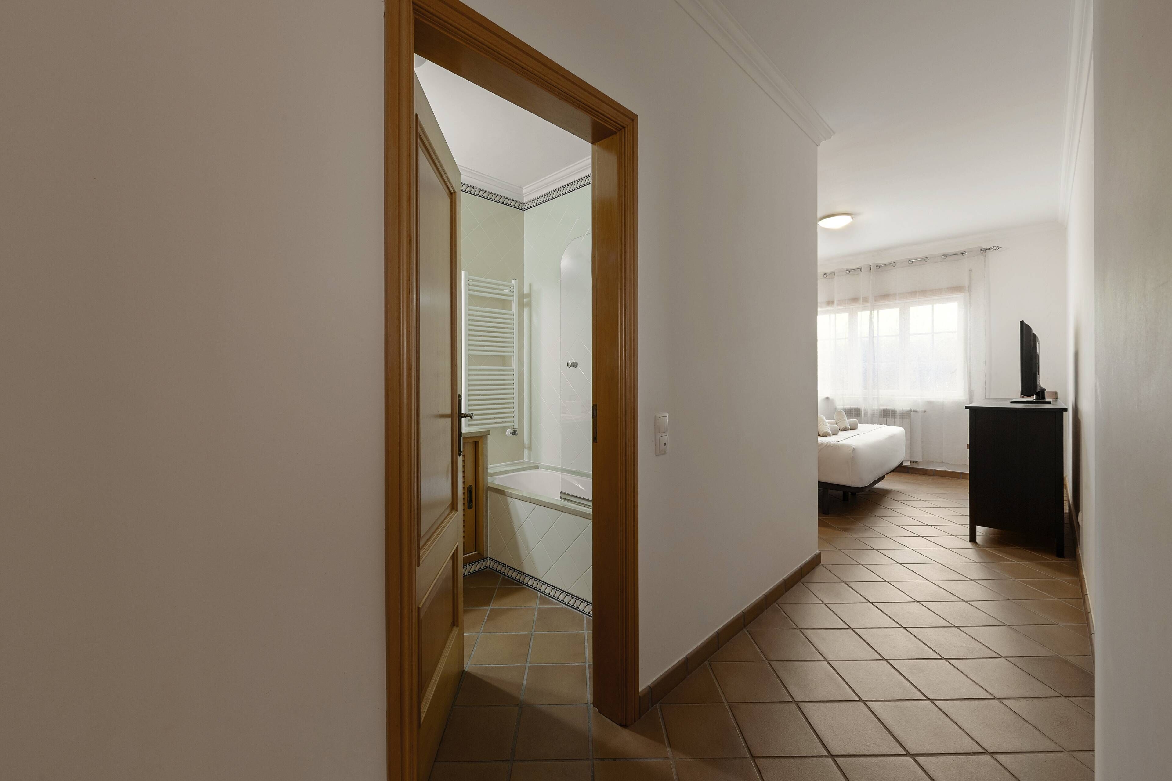 A hotel room with a bed, a desk, and a bathroom with a shower and toilet.